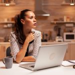 Woman thinking about her career while working on a deadline late at night in home kitchen. Employee using modern technology at midnight doing overtime for job, business, busy, career, network, lifestyle ,wireless.