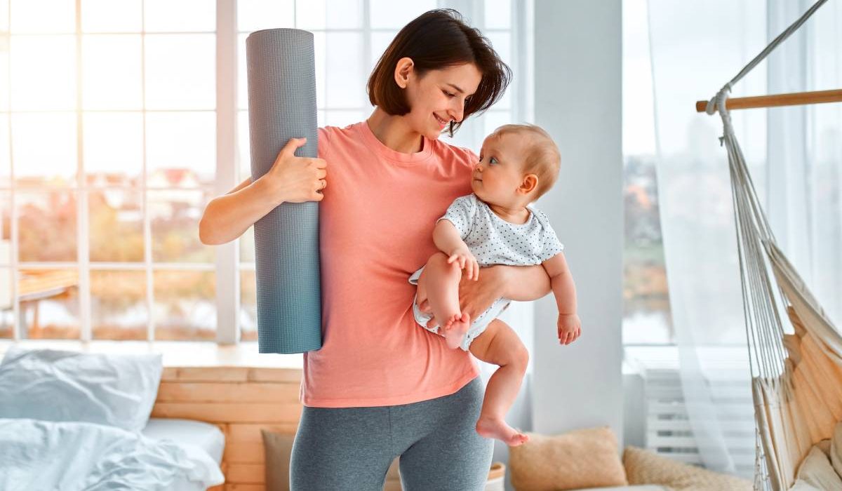 A sports mother is engaged with the child in fitness and yoga at home. The concept of sports, motherhood and an active lifestyle. Young woman in sports training with her child.