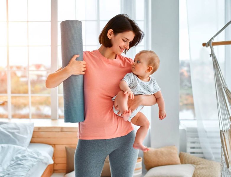 A sports mother is engaged with the child in fitness and yoga at home. The concept of sports, motherhood and an active lifestyle. Young woman in sports training with her child.