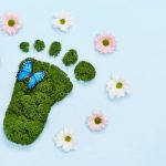Creative eco, environmental care, earth day concept. Barefoot footprint made of natural green moss, flowers and butterfly on blue background. (Creative eco, environmental care, earth day concept. Barefoot footprint made of natural green moss, flowers