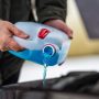 driver refilling the blue non-freezing windshield washer liquid in the tank of the car, closeup