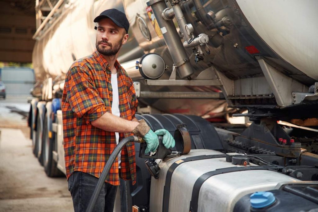 Young truck driver in casual clothes is refueling the vehicle.