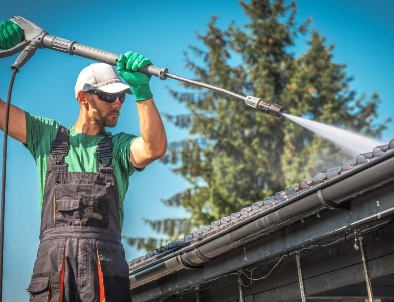 Washing Plastic Transparent Carport Roof by Caucasian Men. Pressure Washer gutter cleaning.