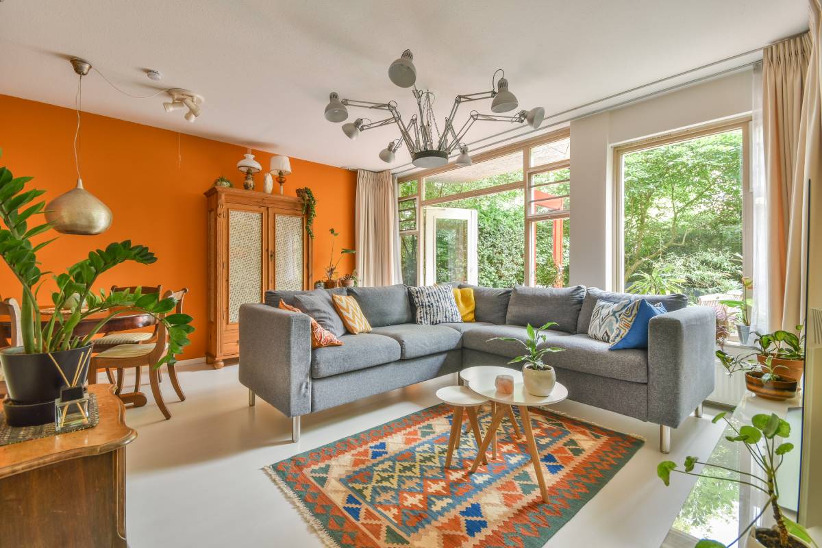 Cozy interior design of living room furnished with comfortable couch and wooden table decorated with carpet and lamp in modern apartment